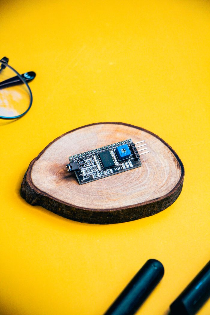Microcontroller on a wooden slice with a vibrant yellow background, ideal for tech and electronics themes.